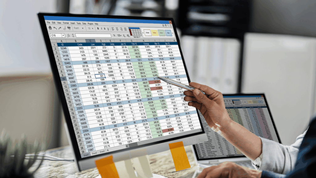 Manufacturing manager pointing at inventory and production data across two screens, a sign of a business that has outgrown spreadsheets