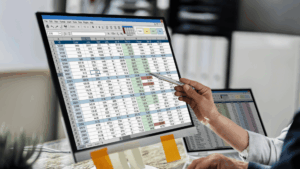 Manufacturing manager pointing at inventory and production data across two screens, a sign of a business that has outgrown spreadsheets