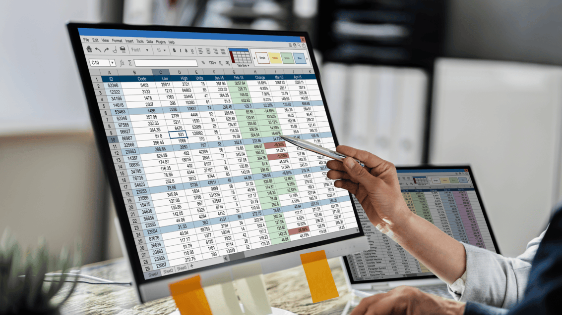 Manufacturing manager pointing at inventory and production data across two screens, a sign of a business that has outgrown spreadsheets
