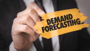 Businessperson in a suit writing “Demand Forecasting” on a glass screen inside an orange brushstroke